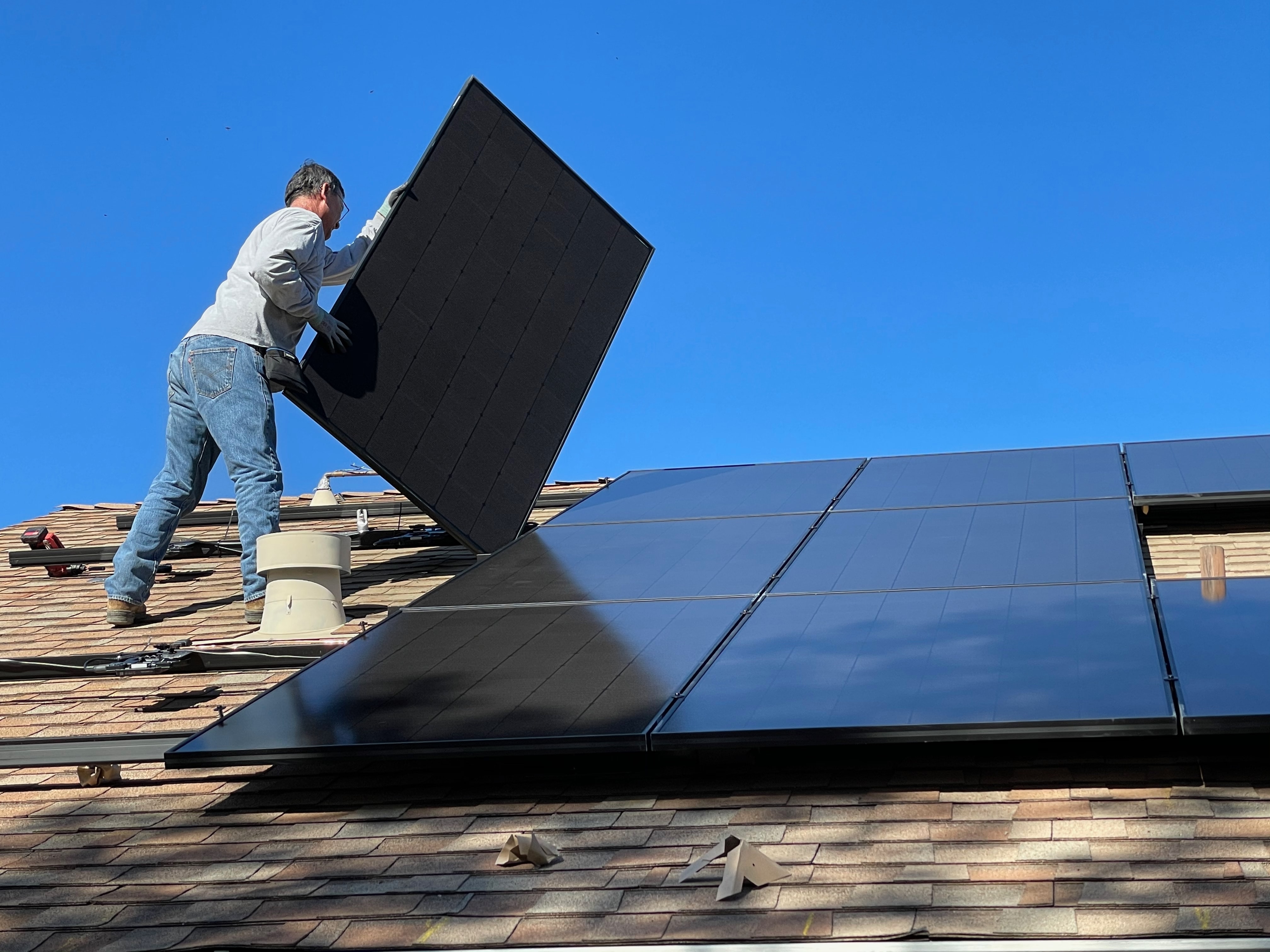 Mann installiert Photovoltaik-Anlage auf dem Dach